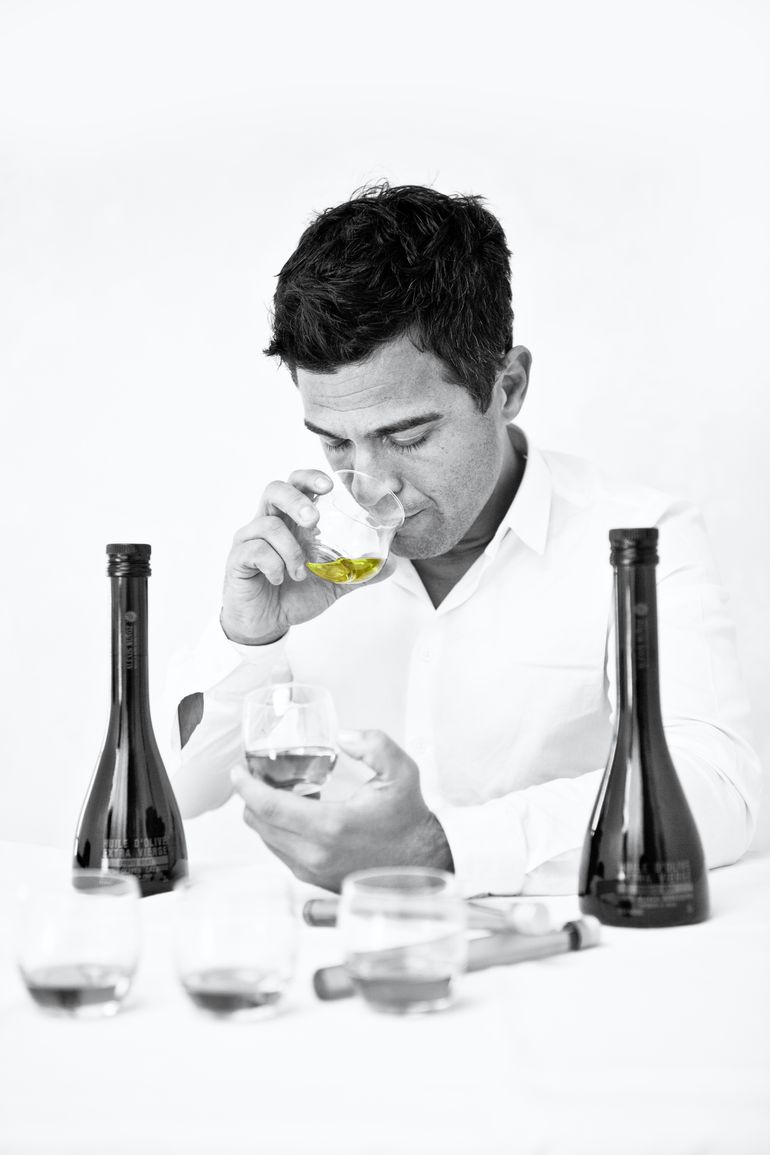 Black and white photo of Alexis Muñoz tasting olive oils in a production facility.