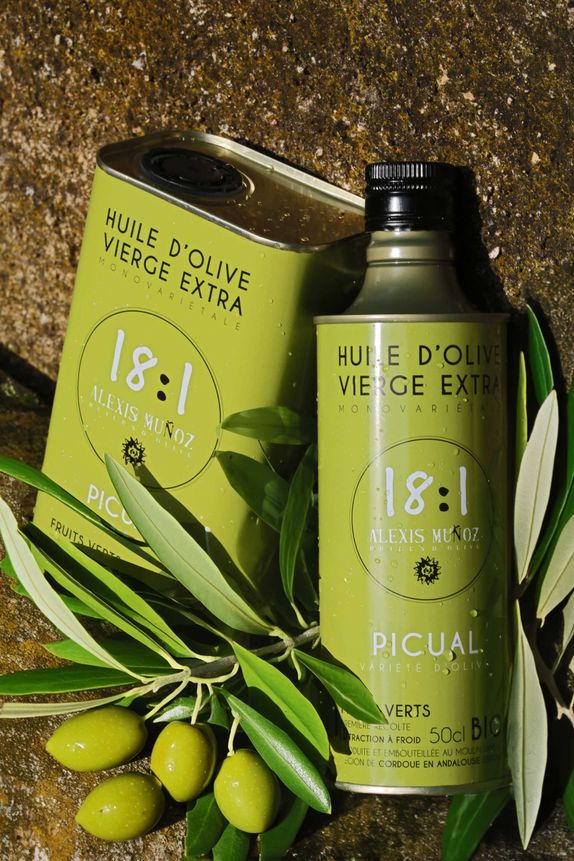 500ml and 1L cans of olive oil from the Alexis Muñoz brand, green in color, placed on a stone background with olive branches.