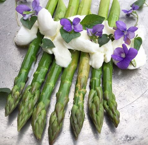 Asperge dressées avec des fleurs commerstibles violettes, un fromage crémeux comme une buratta et de l'huile d'olive 18:1 produite par Alexis Muñoz
