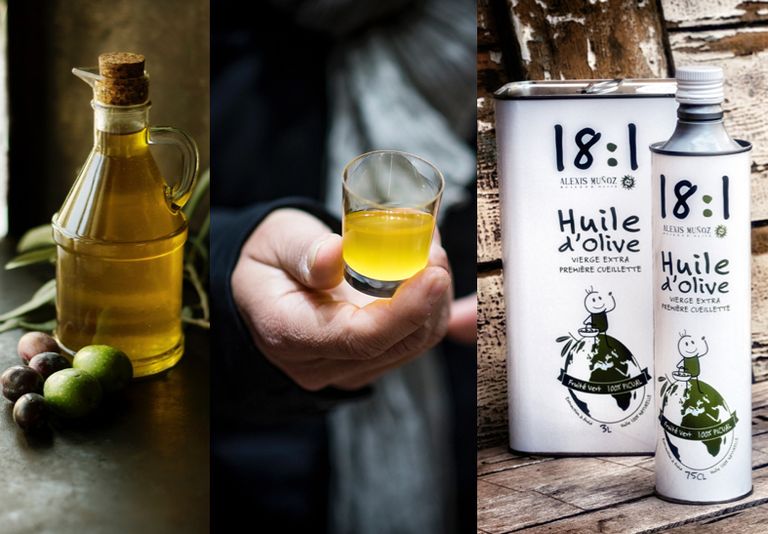 Transparent bottle of olive oil, close-up of Alexis Muñoz's hand holding an olive oil tasting cup and a square white olive oil can from the Alexis Muñoz 18:1 brand.