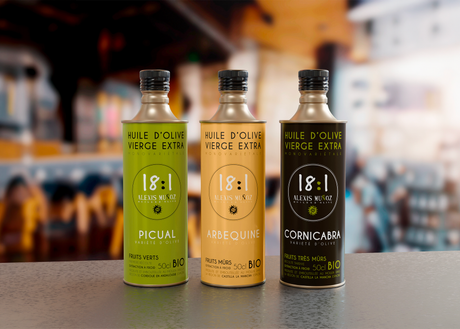 The image shows three monovarietal olive oils by Alexis Muñoz 18:1 Picual, Arbequina, and Cornicabra - in 50 cl bottles.