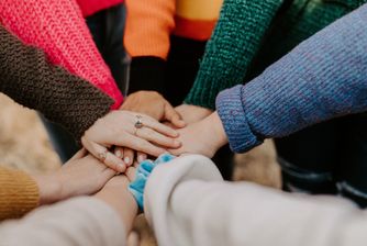 Close-up of about ten hands coming together to celebrate teamwork.