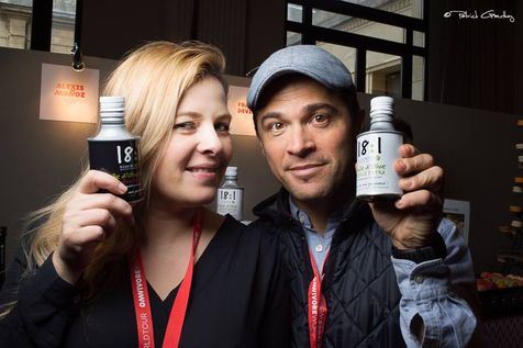 Alexis Muñoz et Betty Guillo au Omnivore World Tour Paris 2016, avec dans leur main un bidon blanc et noir d'huile d'olive 18:1, de la marque Alexis Muñoz, face au Stand du salon.
