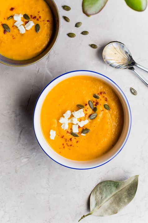 Bol de soupe de courge, graines de courges et féta dans un bol blanc et bleu